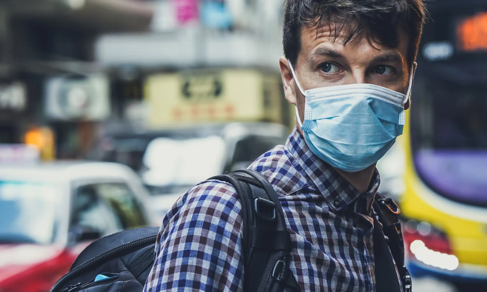 Man on a busy street wearing a face mask